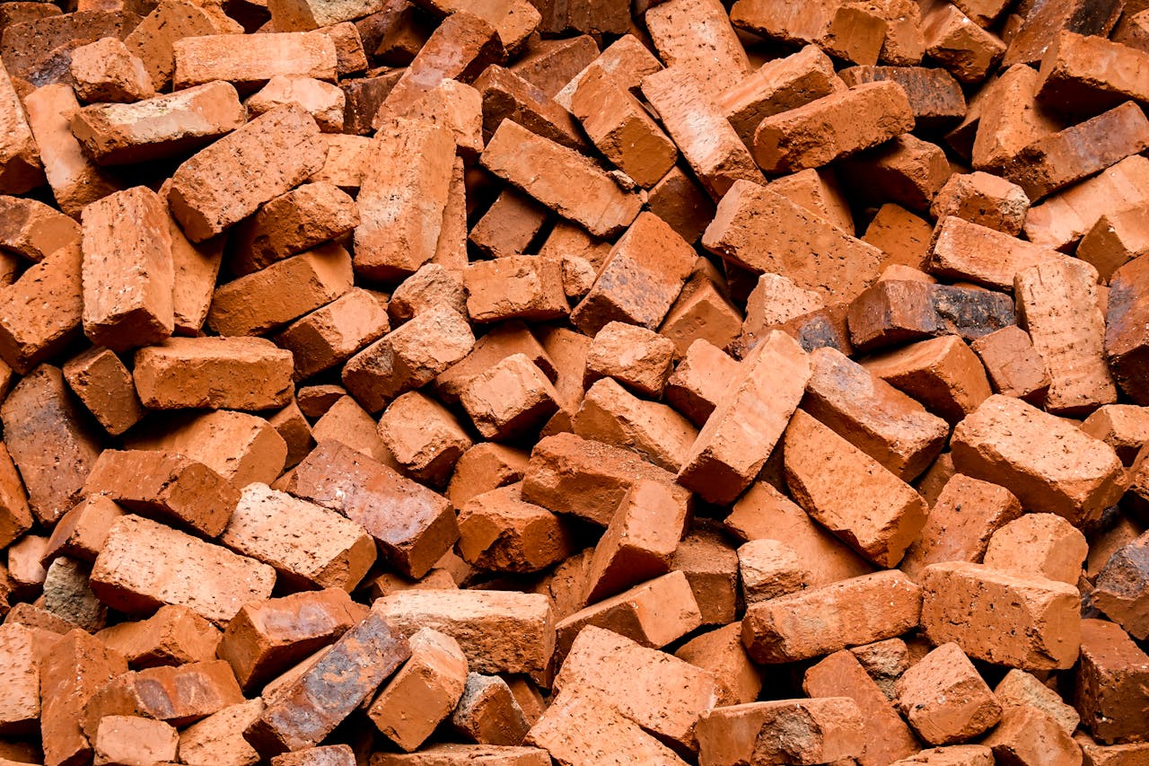 Services-02 High-quality close-up image of a large pile of red clay bricks, ideal for construction projects.
